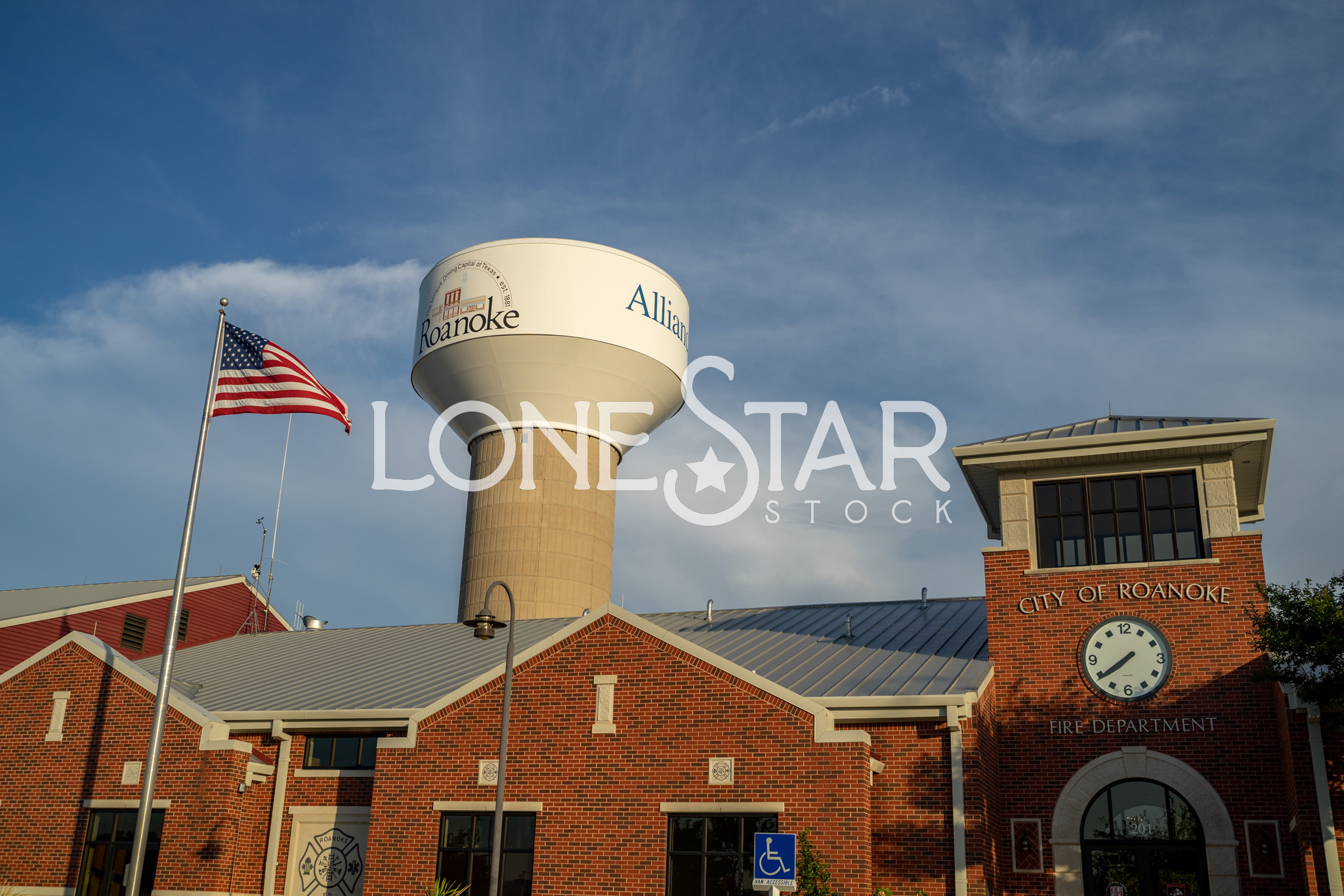 Preview of American Flag at Roanoke Fire Department Brick Building with Water Tower in Background